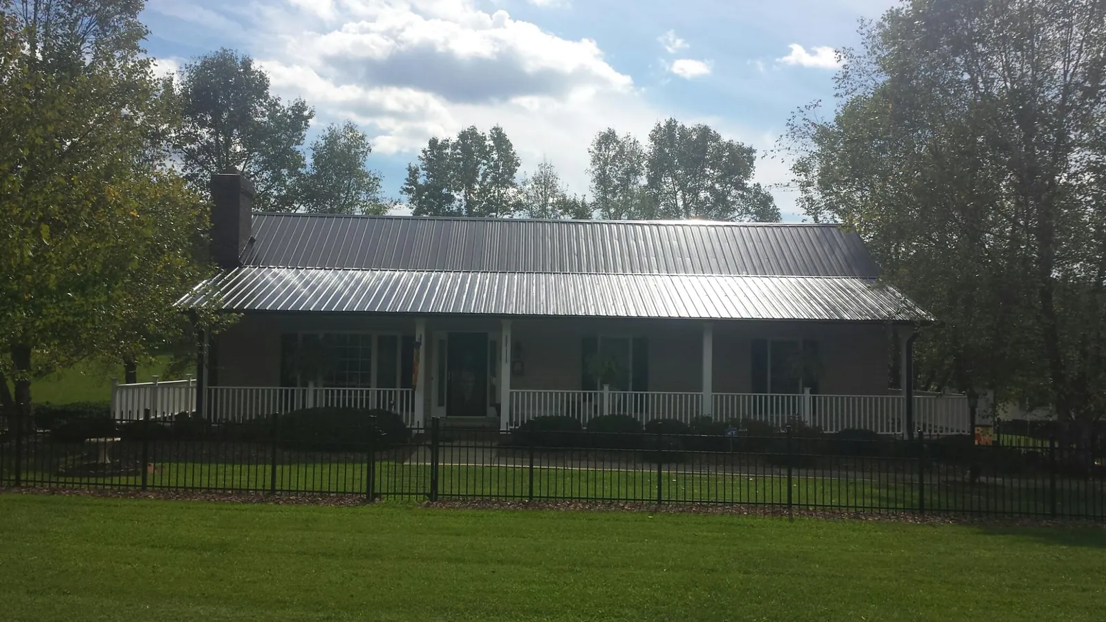 Gray metal roof on a brick ranch with a full width front porch — Gutter Guard Installation work by our crew in Shawnee