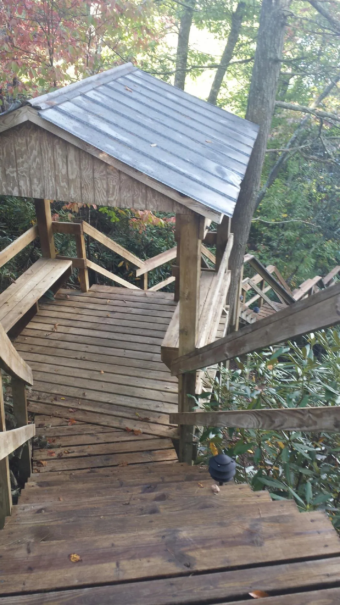 Metal roofed shelter over wooden steps on a wooded walkway — Skylight Repair & Installation work by our crew in Shawnee
